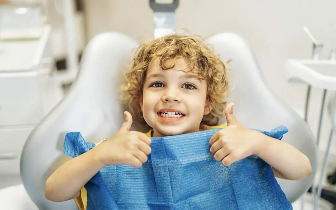 Happy young child giving two thumbs up in the dental chair at Monroe Family & Cosmetic Dentistry